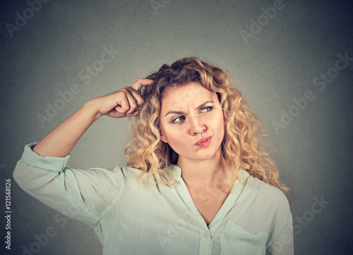 Woman scratching head thinking about something looking up