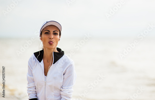 Young woman on beach listening to music in earphones from smart phone mp3 player smartphone armband  Female training for marathon on beautiful beach. Mixed race Asian woman.