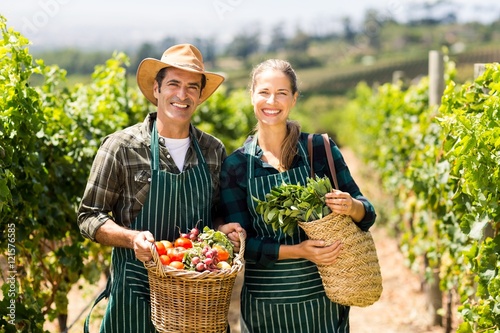Tableau sur toile Portrait of happy farmer couple holding baskets of vegetables