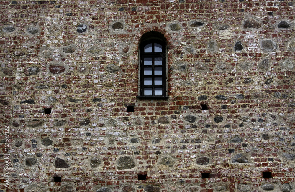 Long window with bars in the old stone wall
