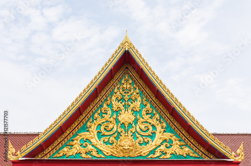 golden ancient texture on emerald wall infront of temple roof.