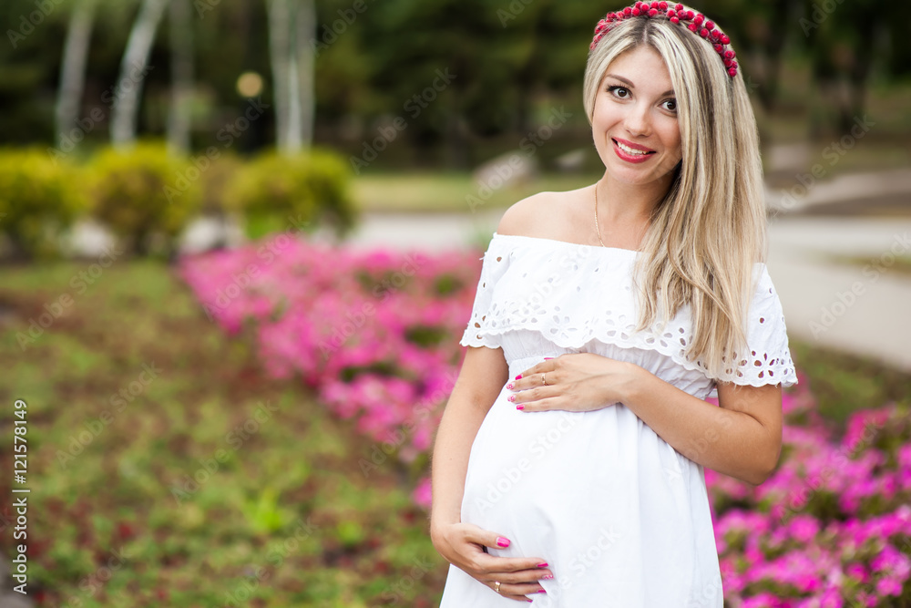 Fototapeta premium Beautiful lovely girl wearing her first child in the stomach and is looking forward to his birth. Strolling in the park, enjoy nature and quietness