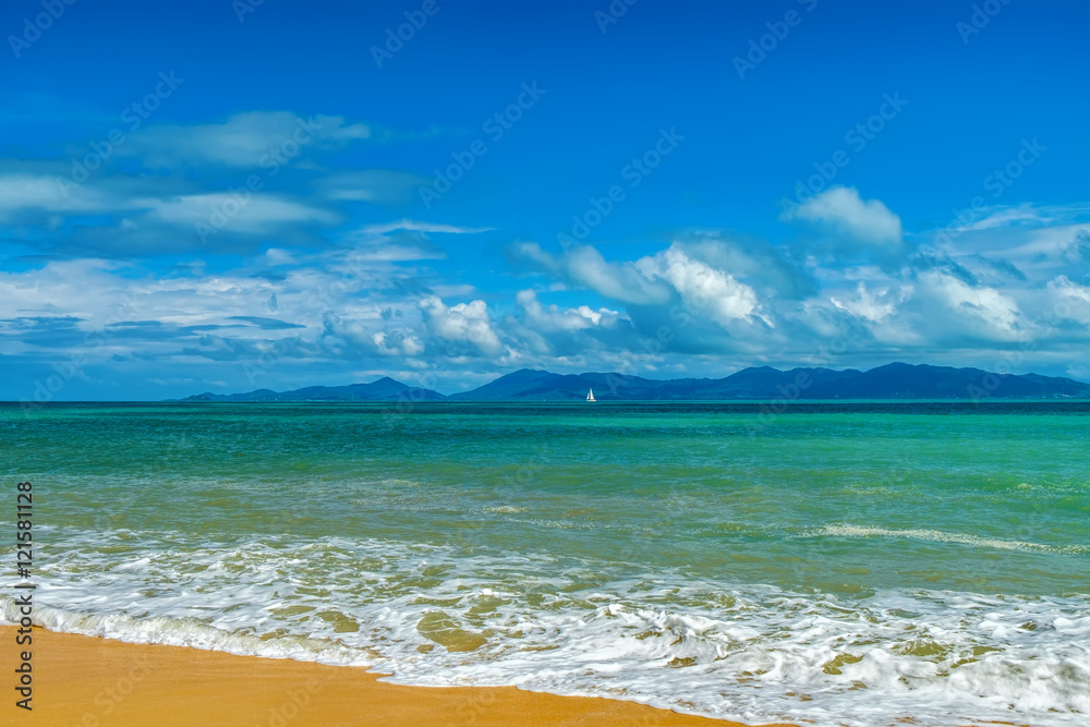 Sunny day with blue cloudy sky at tropical beach and sailboat on the horizon, Koh Samui, Thailand