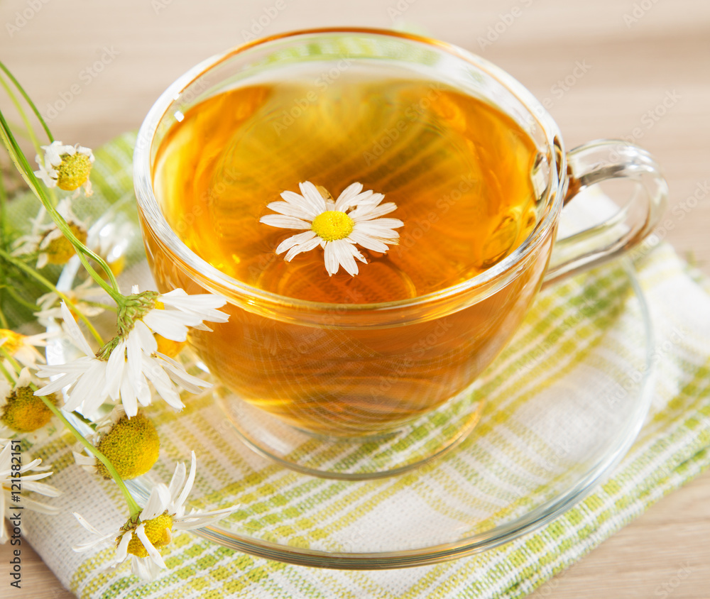 Chamomile tea in a transparent cup and a bouquet of daisies Chamomile tea in a transparent cup and a bouquet of daisies