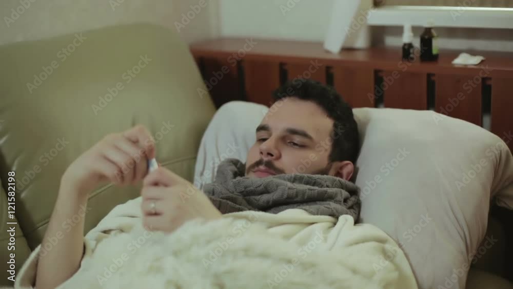 An ill man measuring his temperature. An ill man measuring his temperature.