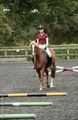 A young pony rider walking a pony - September 2016 - A Chestnut pony and rider stepping between and over poles laid on the ground