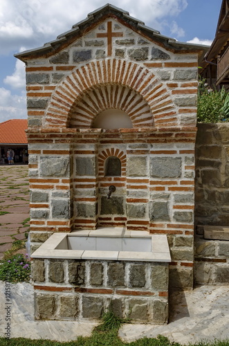 View of inner part yard with spring water fountain in restored Montenegrin or Giginski monastery St. St. Cosmas and Damian, mountain Kitka, Breznik, Pernik region, Bulgaria 