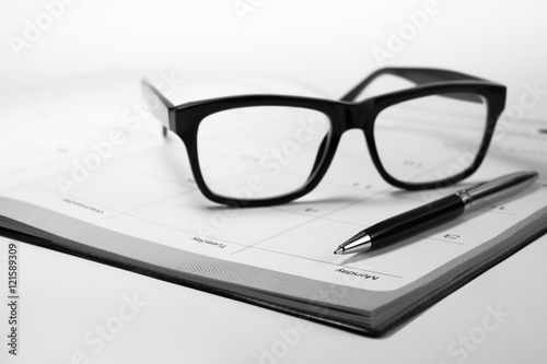 Glasses and pen on business graph chart paper with calendar.