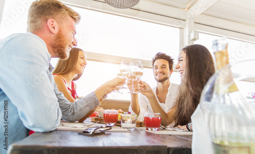 Happy friends celebrating toasting with wine photo