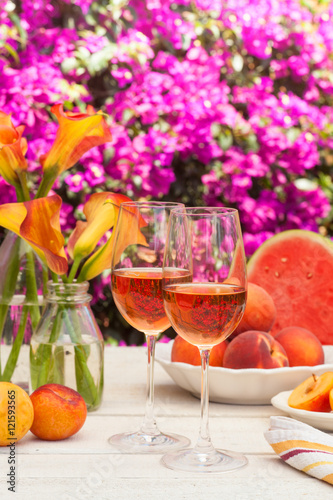 glasses of rose wine, peaches, plums and watermelon at a picnic in the summer