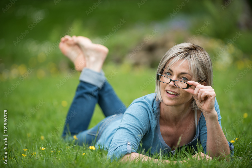 portrait of a woman of fifty years old lying in grass in park