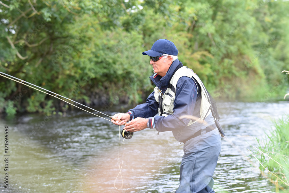 Fly fisherman fishing in river to catch brown trout Fly fisherman fishing in river to catch brown trout