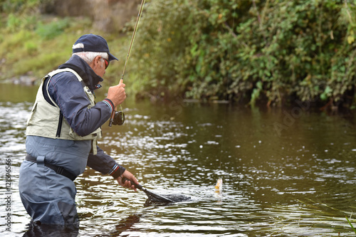 Fly-fisherman catching trout in irish river