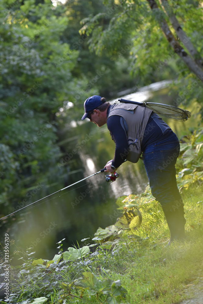 Obraz premium Fisherman fishing in river from riverbanks