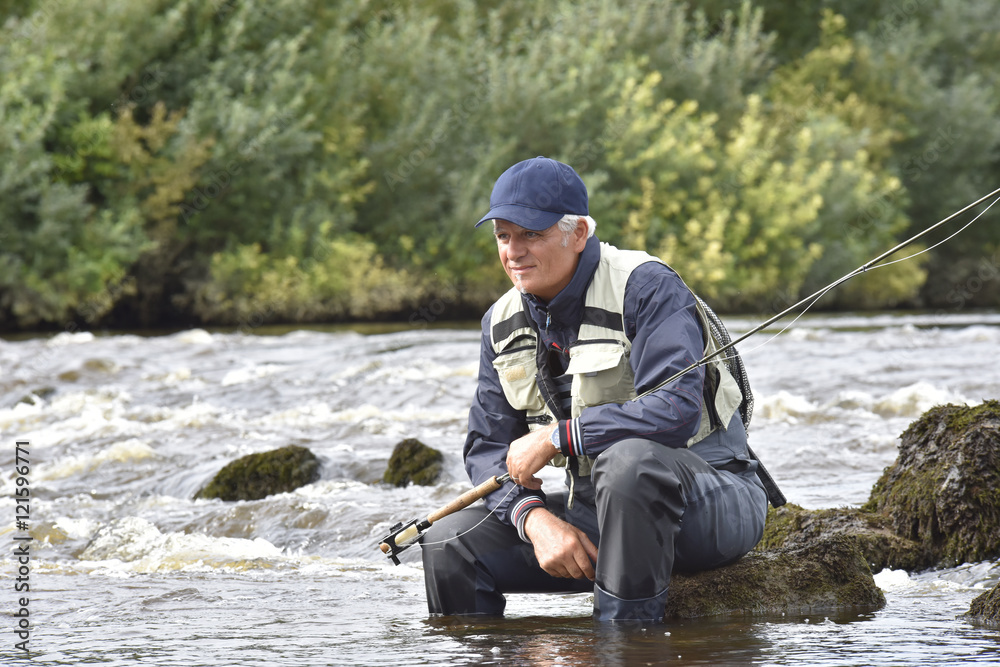 Fly-fisherman waiting with fishing pole on shoulder Fly-fisherman waiting with fishing pole on shoulder