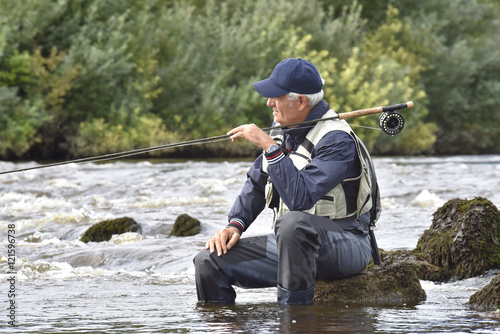 Fly-fisherman waiting with fishing pole on shoulder