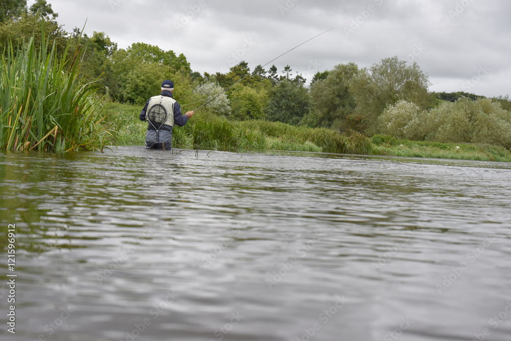 Back view of fly-fisherman fishing in river Back view of fly-fisherman fishing in river