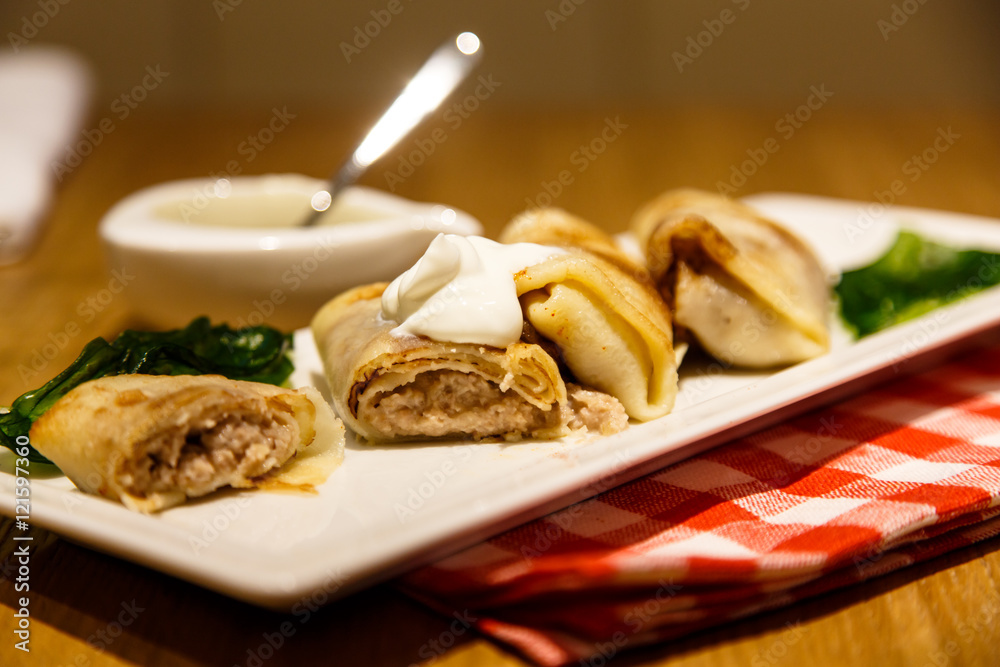 Rolls of Russian pancakes stuffed with meat with sour cream.