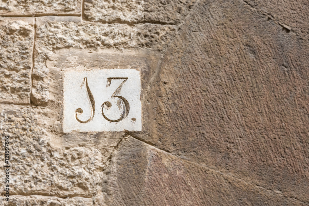 A house number thirteen (13) on a wall in Girona