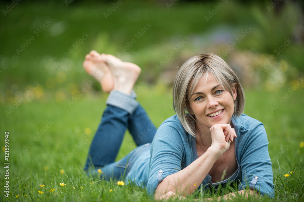 the portrait of a woman of middle aged lying in grass in park the portrait of a woman of middle aged lying in grass in park