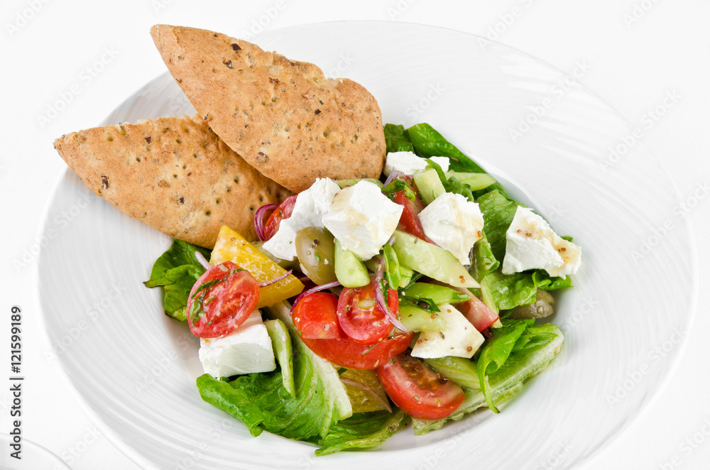 Greek salad with feta cheese, Ligurian olives and tortilla pea and hummus on a plate on a white background, closeup