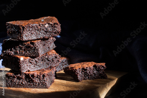 Chocolate brownie on the black background, side view, selective focu