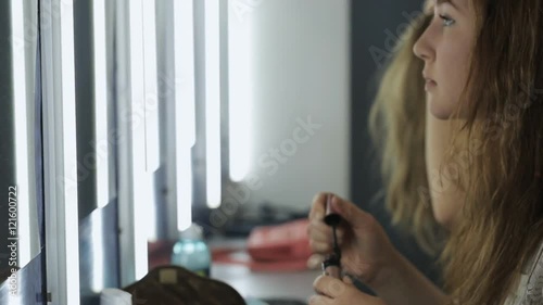 Group of pretty girls sits in front of mirror and smartens up for going out. photo