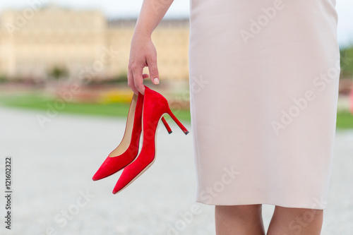 Elegant woman holding red high heels shoes in her hands