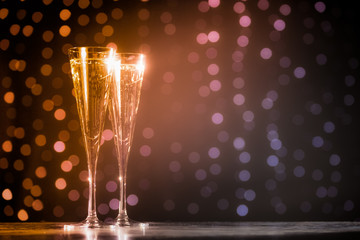 Two glasses of champagne on dark bokeh background