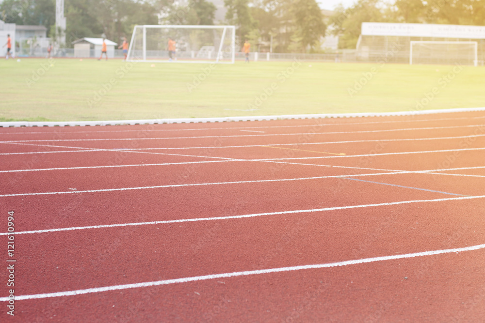Fototapeta premium Running track around the football field with the evening sun