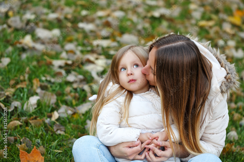 Mother embraces and kisses daughter. Autumn.