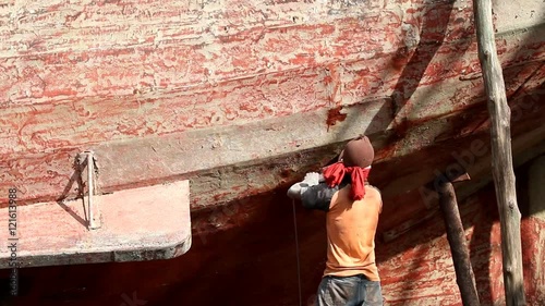 Boat Hull repairs/ A man using grinder in preparation for anti foul paint being applied photo