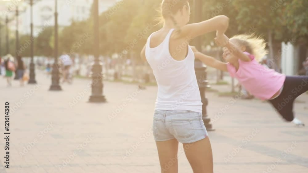 Joyful mother whirls little daughter, laughing and hugging her