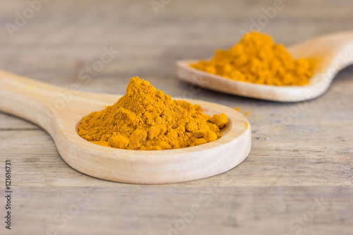Turmeric powder in wood spoon on white background photo