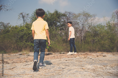Two Boy walking on the rocky land.