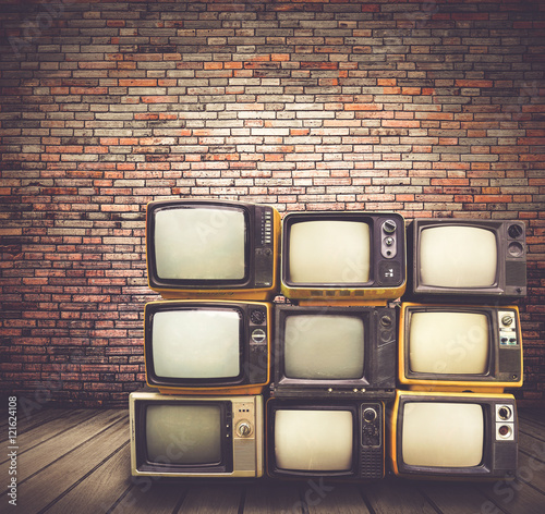 Antique and vintage style photo. retro televisions pile on floor in old room. photo