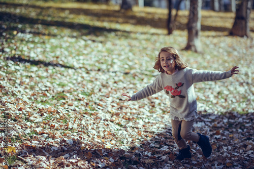 Little girl playing in a city park in autumn