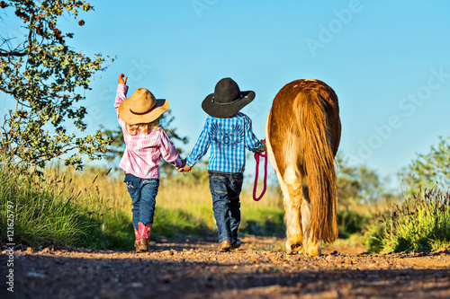 Foto Little cowgirl and cowboy with pony