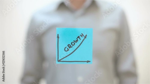 Growth. A man sticks a note on transparent screen