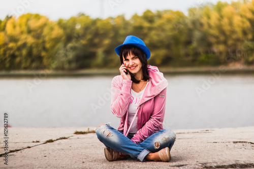 Beautiful brunette by the river bank on the phone.