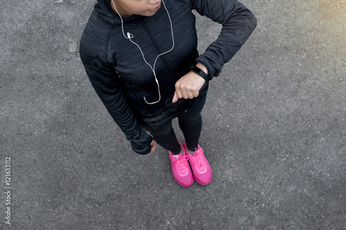 Overhead view of young unrecognizable female checks activity tracker during outdoor exercise
