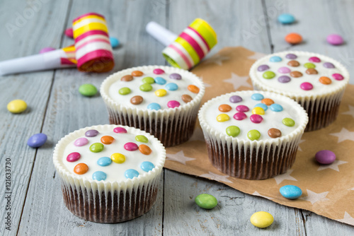 Chocolate cupcakes glazed with smarties, wooden background