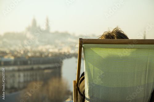 Person sitting in deckchair, looking at view of city
