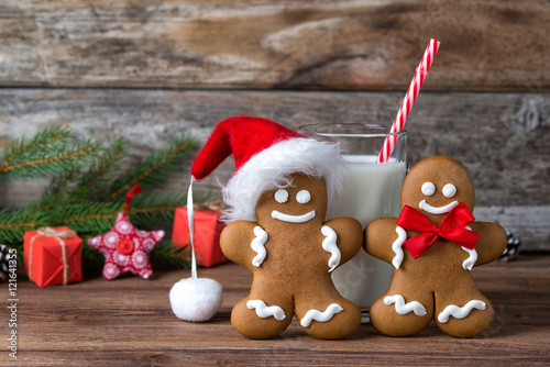 Gingerbread men in Santa hat and glass of milk