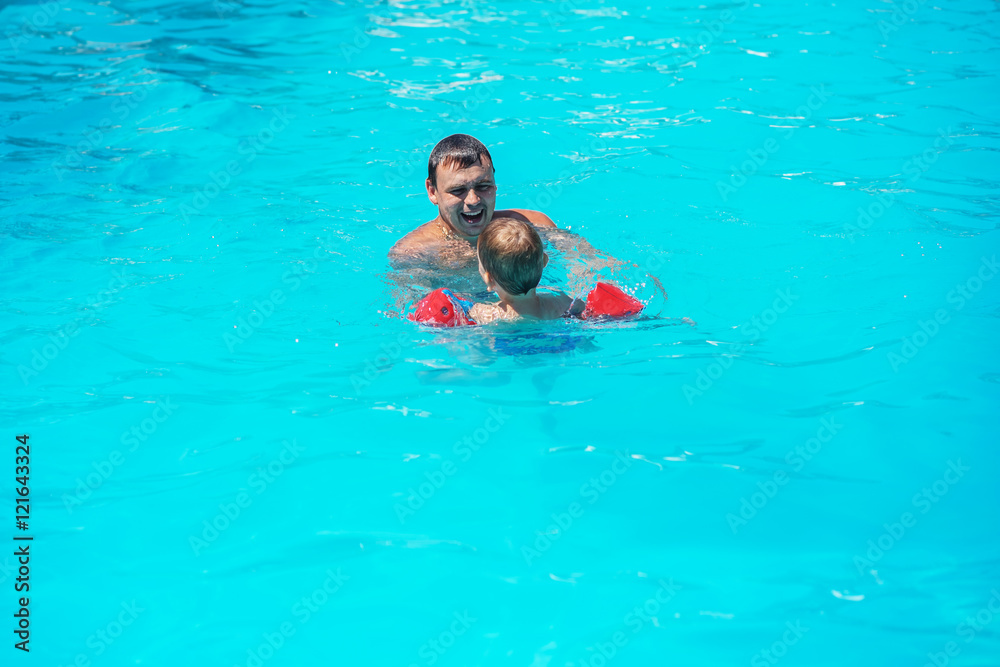 Dad and son swimming together in the pool