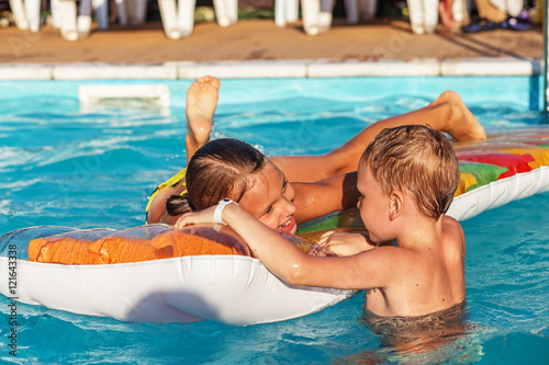 Happy kids playing in blue water of swimming pool. © nata_zhekova