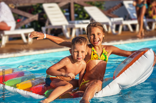 Happy kids playing in blue water of swimming pool.