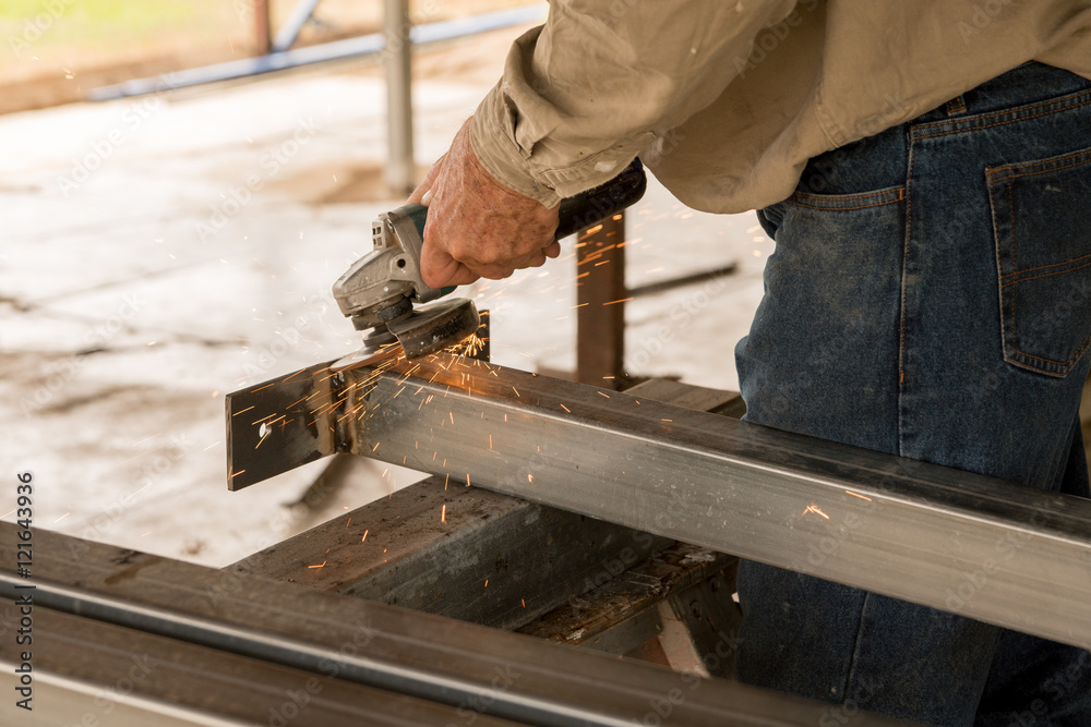 Builder making steel stumps using a grinder