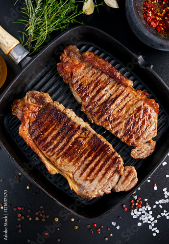 Fresh cooked meat Beef Steak Sirloin for two. in iron grilled pan with herbs.