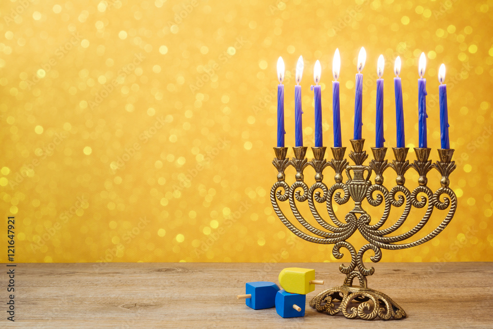 Fototapeta premium Jewish holiday Hanukkah background with vintage menorah and spinning top dreidel over lights bokeh.